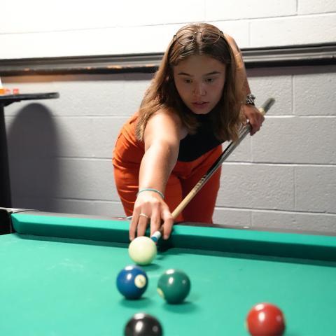 Student lining up for shot on billiards table in the MUB Games Room.