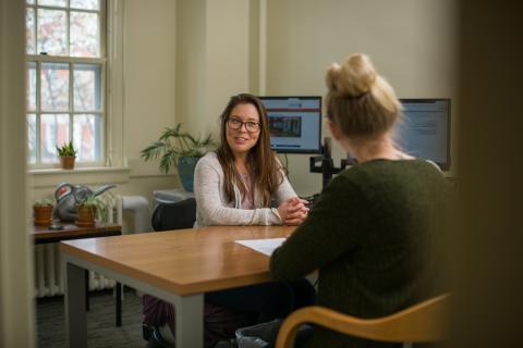 Student sitting at desk speaking with an academic advisor 